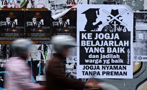 Sejumlah pengendara melintas di dekat poster himbauan bertuliskan "Ke Jogja Belajarlah Yang Baik dan Jadilah Warga Yang Baik, Jogja Nyaman Tanpa Preman" yang terpasang di jalan Cendana, Yogyakarta, Minggu (1/4).