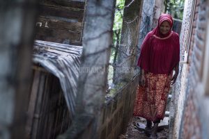 Aminah harus berhati-hati berjalan melalui celah dinding dan pagar yang menghubungkan ke rumahnya_FOTO Oviyandi Emnur