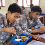 Salah seorang siswa di SMKN 1 Kota Lhokseumawe menikmati makanan bergizi gratis. Foto: AJNN/Putri Zuhra Furna.