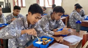 Salah seorang siswa di SMKN 1 Kota Lhokseumawe menikmati makanan bergizi gratis. Foto: AJNN/Putri Zuhra Furna.